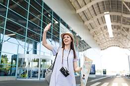 Traveler tourist woman with retro vintage photo camera, paper map waving hand for greeting, meeting friend and catch taxi at airport. Passenger traveling abroad on weekend getaway. Air flight concept